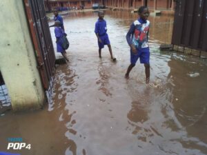 Pupils of Asoro Public Primary School, in Benin, Edo State, wading through flood water on Monday