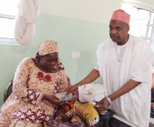Kano state Commissioner for Health, Dr. Labaran, handing over N10, 000 assistance to the mother of one of the 78 malnourished children admitted at the Ungwar Uku Primary Healthcare Centre as directed by Governor Yusuf