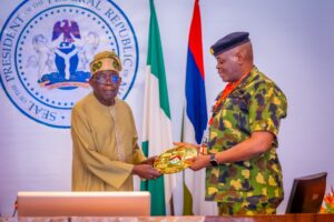 President Tinubu receiving the report from Colonel Olajide Bello on behalf of the NDA delegation.jpg
