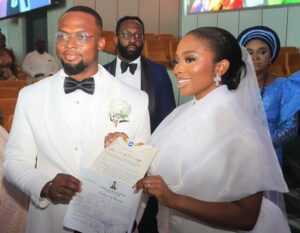 Tobiloba, right, and Ayodele displaying their wedding certificate in church.jpg