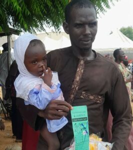 Ubale carrying his daughter, Hafsat, after immunization in Bunkure on Saturday