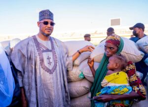 Governor Radda handing over a bag of grain to a vulnerable mother and her child