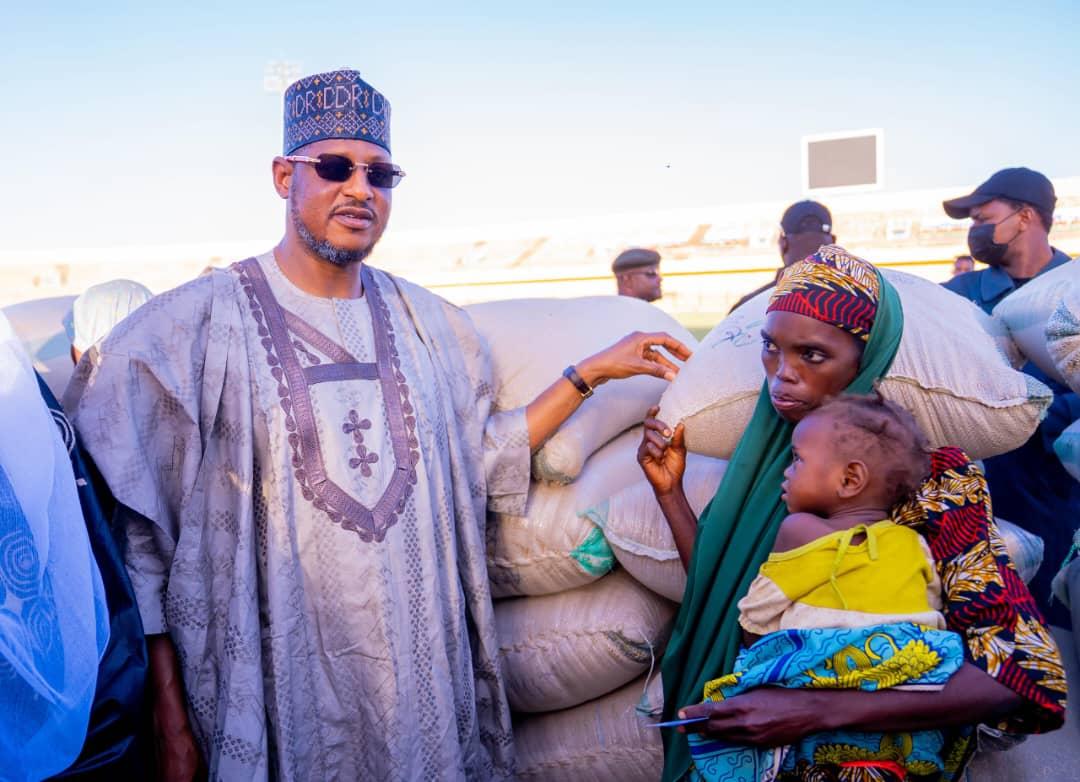 Governor Radda handing over a bag of grain to a vulnerable mother and her child