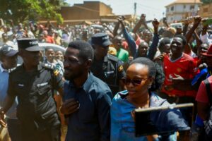 Ugandan presidential candidate Robert Kyagulanyi (Bobi Wine), of the National Unity Platform party, flanked by his wife Barbara Kyagulanyi, are escorted by police and supporters as they arrive to cast their votes in the general election, within the Magere neighborhood of the Kasangati district in Kampala, Uganda, on January 15, 2026. Thomas Mukoya/REUTERS