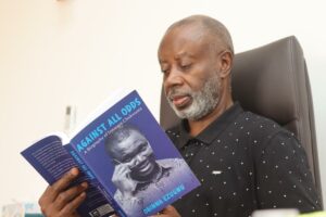 Dr Chido Onuma reading a copy of Against All Odds