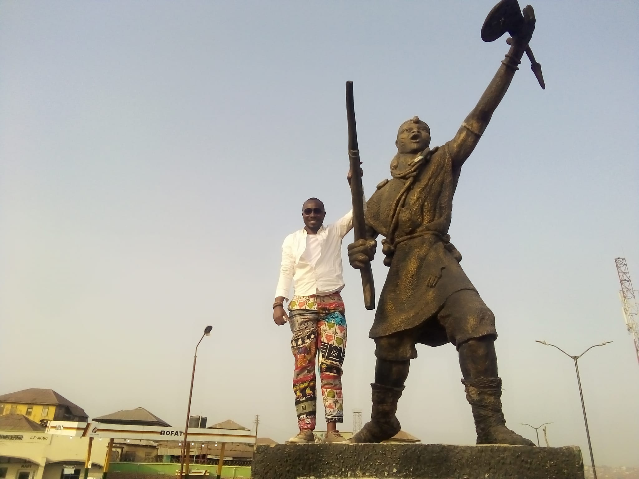 Oladeinde Olawoyin standing by the Iba Oluyole statue